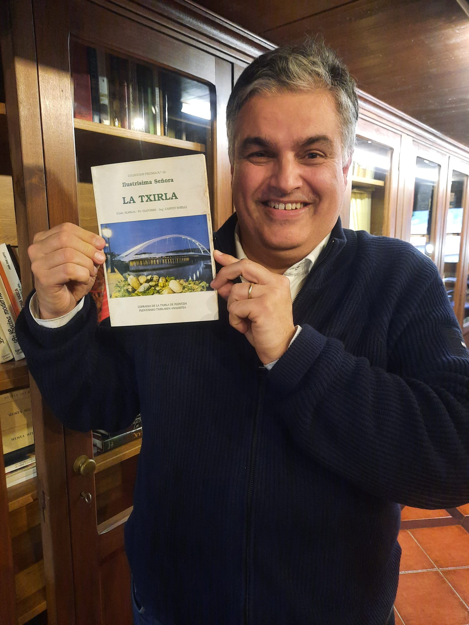 Yo mostrando un libro dedicado a la txirla, editado por la Cofradía de la Txirla de Plentzia, en la biblioteca de la Cofradía Vasca de la Gastronomía. 